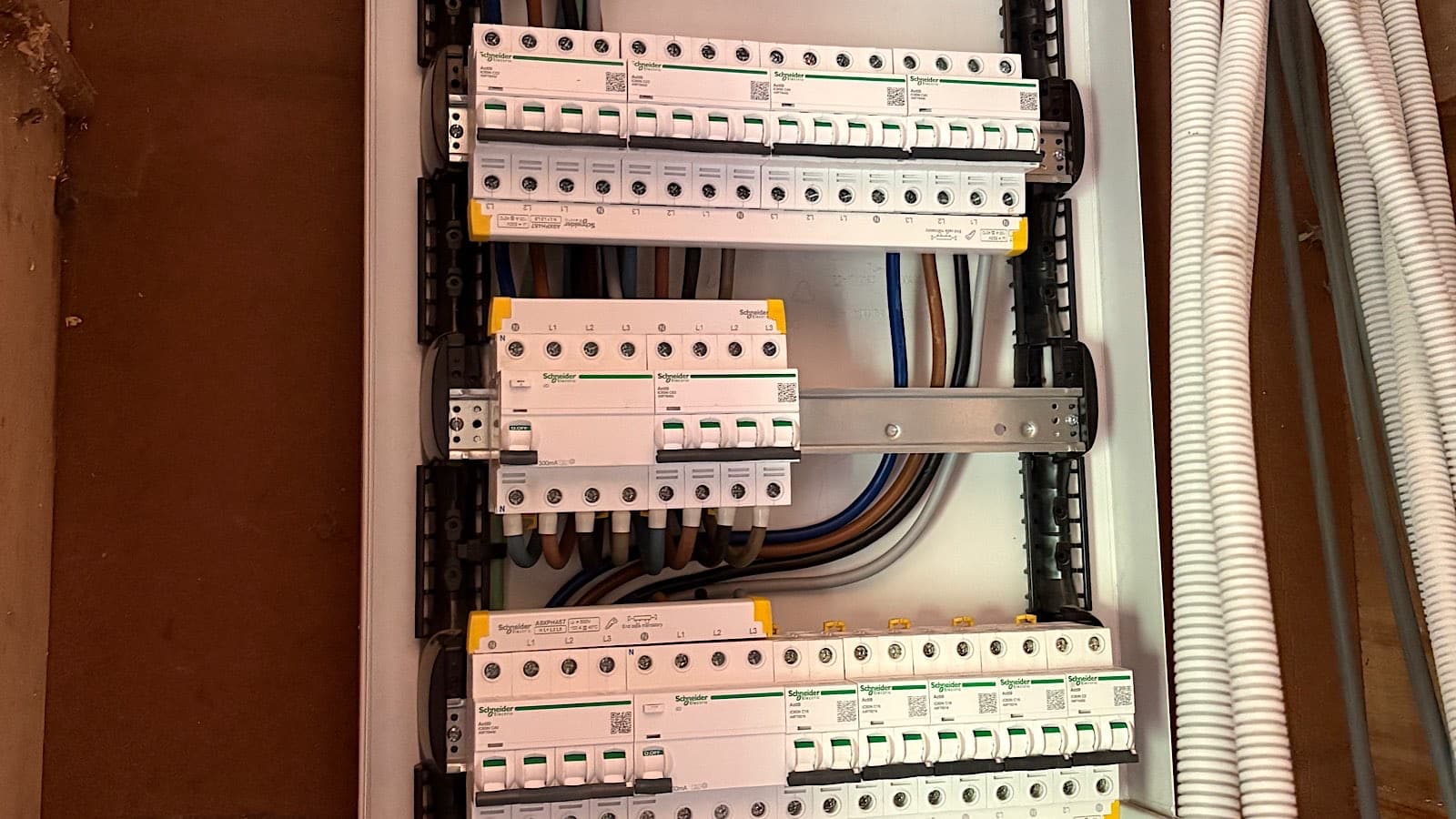 Tableau triphasé ouvert : trois rangées de protections Schneider, arrivées préparées